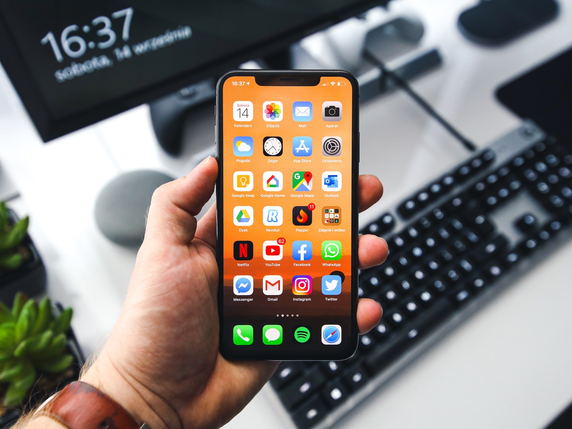 Man Holding iPhone against Computer Background