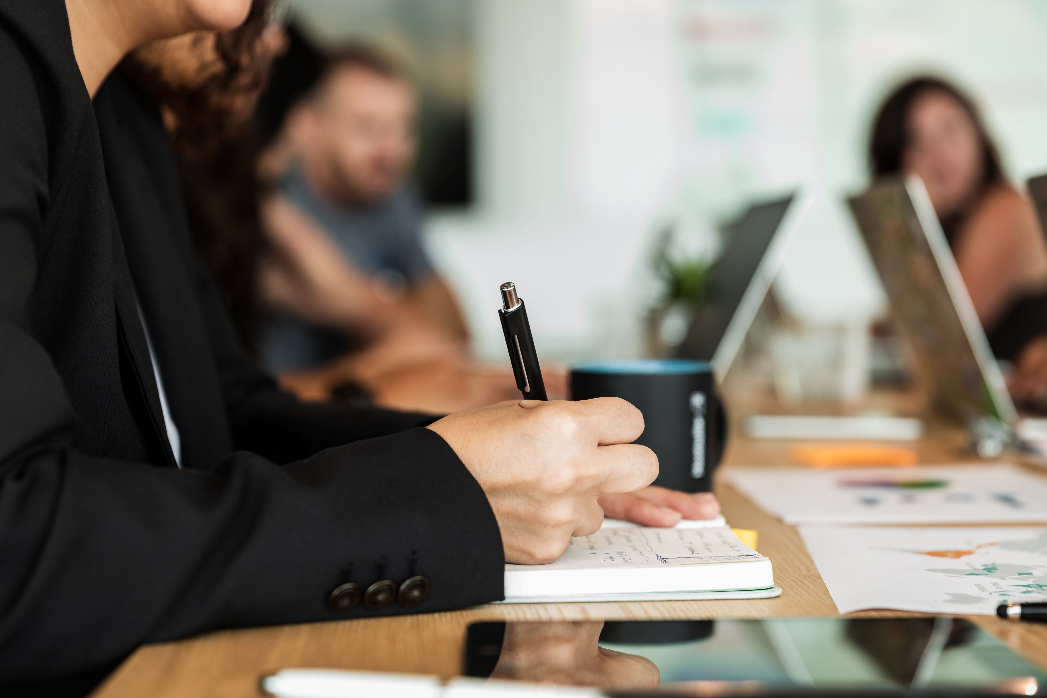 woman-writing-in-notebook-during-meeting.jpg